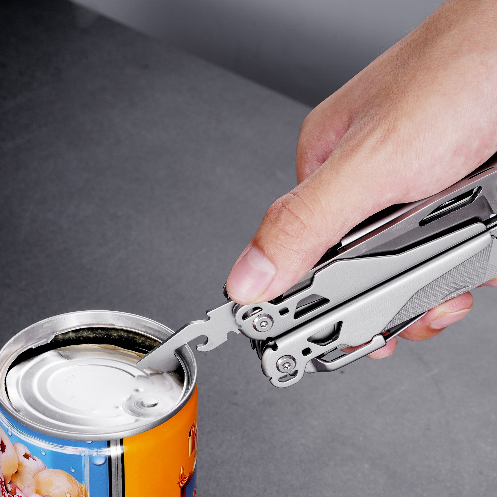 hand using VEVOR multitool pliers to open a can against a gray background.
