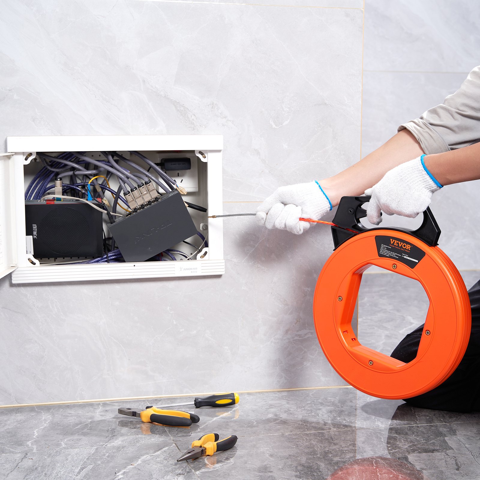electrician using the VEVOR fish tape to guide wires in a control panel cabinet.