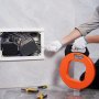 person using VEVOR fish tape to manage electrical wiring inside a wall panel.