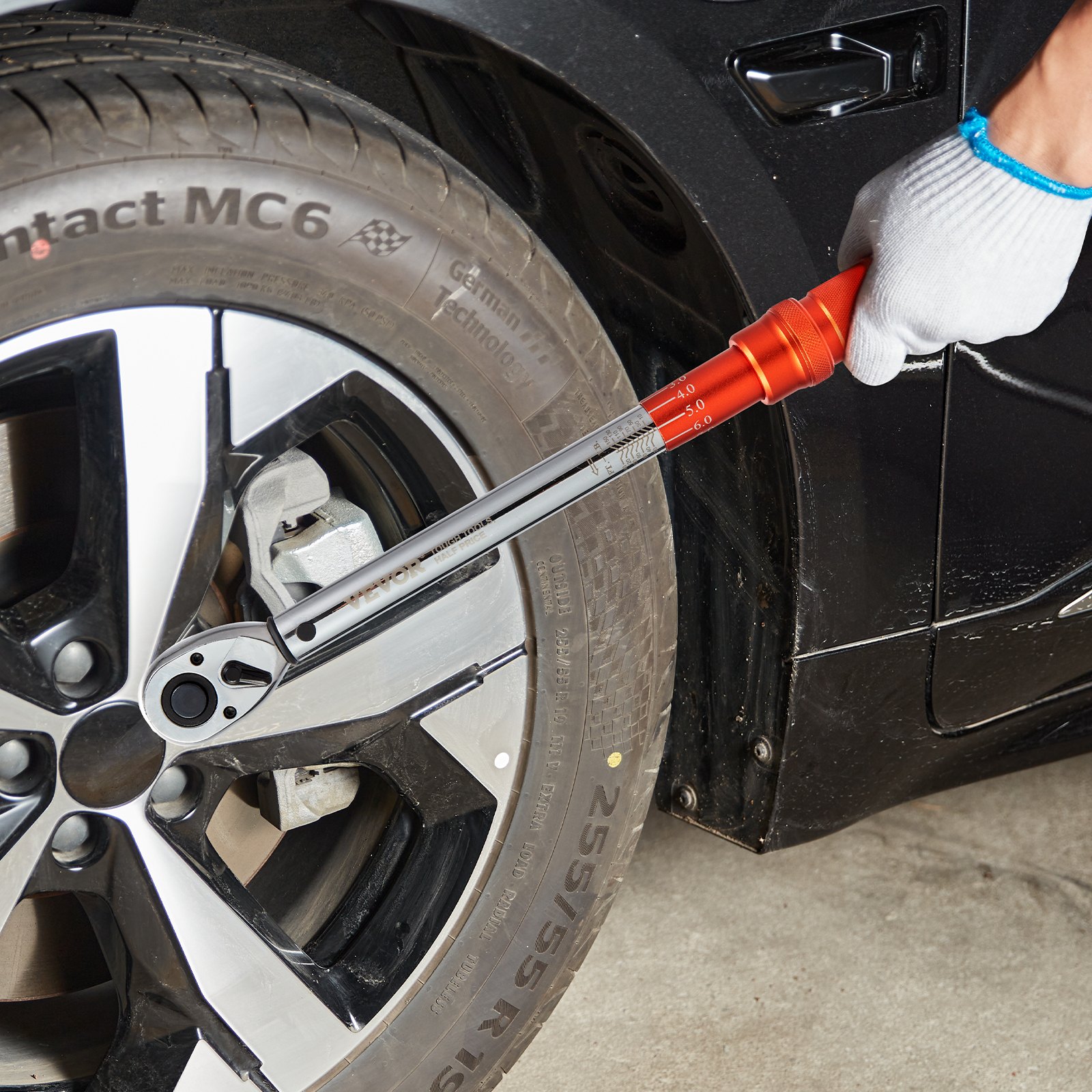 hand using a VEVOR torque wrench on a car wheel with silver alloy rims and continental mc6 tire.