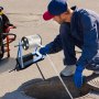 man using VEVOR polyester pull tape for underground work near a manhole with protective gloves.