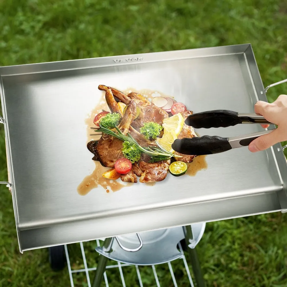grilling meat and vegetables on a VEVOR stove top griddle with tongs, outdoors on green grass.