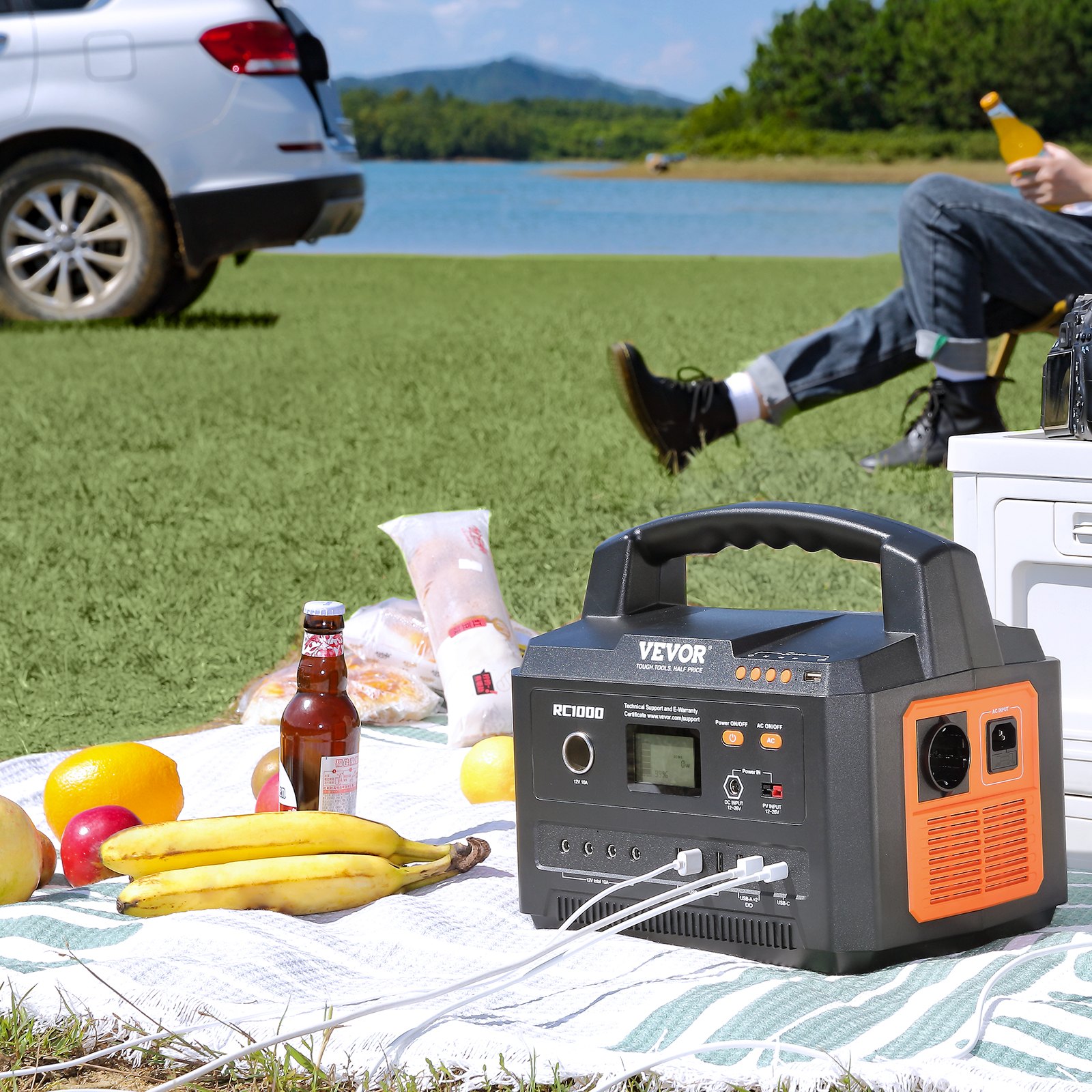 VEVOR portable power station on a picnic blanket by a lake, with fruits and drinks nearby.