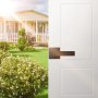 modern VEVOR entry door handle on white door, opening to a sunny garden and charming house.