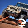 jeep climbing over rocks with a VEVOR tow strap attached for off-road recovery.