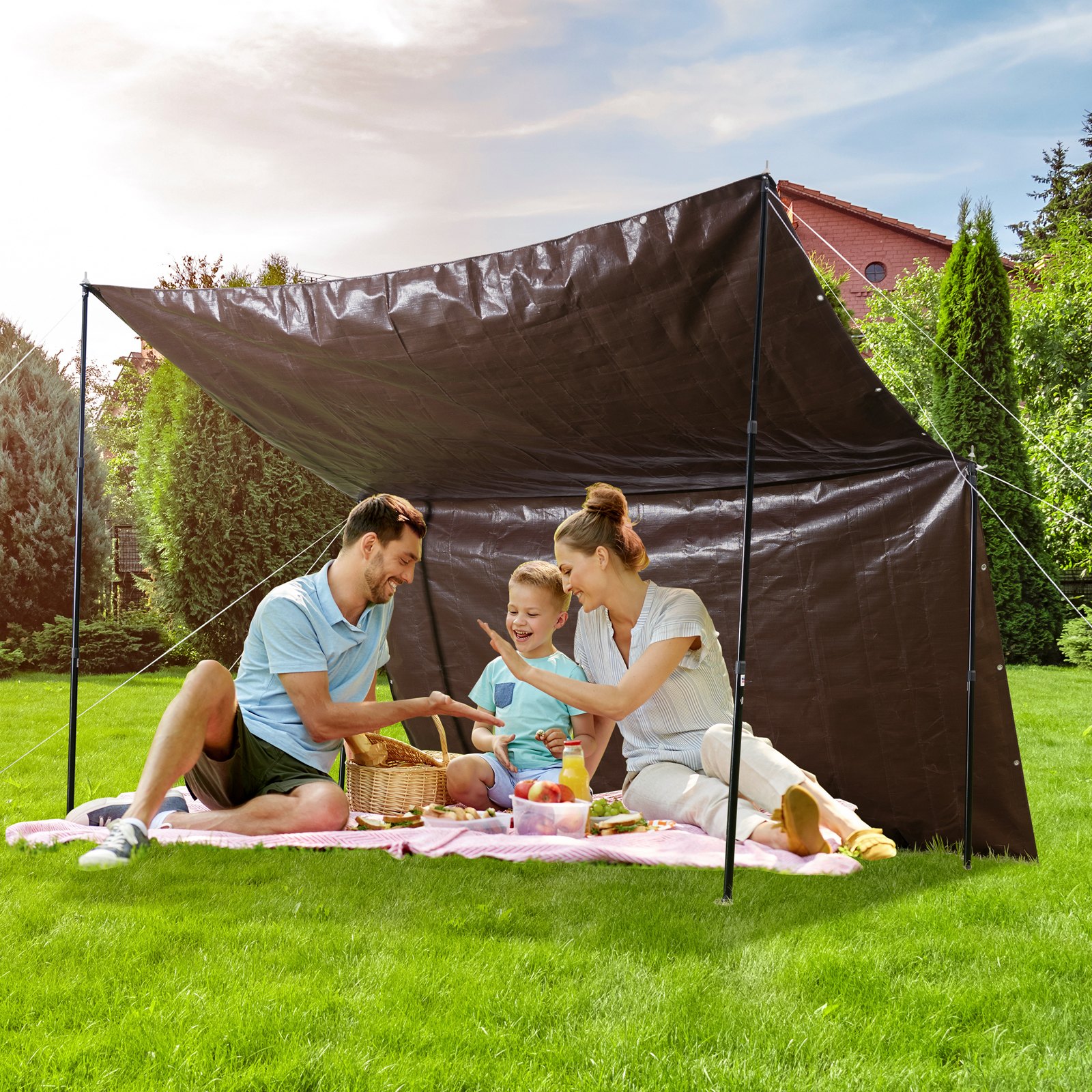 family enjoying a picnic under a VEVOR waterproof tarp set up in a lush garden on a sunny day.