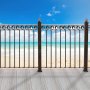 VEVOR metal balusters on a wooden deck overlooking a sandy beach and turquoise ocean under a blue sky.