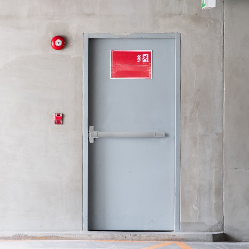 emergency exit with VEVOR push bar door lock, red fire alarm, and exit sign on concrete wall.