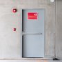 emergency exit with VEVOR push bar door lock, red fire alarm, and exit sign on concrete wall.