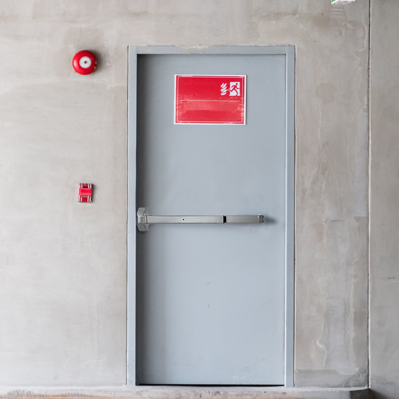gray door with a VEVOR panic exit device, red exit sign above, and fire alarm equipment nearby.