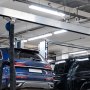 modern garage with vehicles on a rotary lift and bright VEVOR led vapor tight lights illuminating the space.