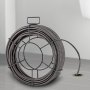 VEVOR drain cleaning cable coiled on the floor with its end inserted in a drain.