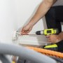 man using a drill to clean a wall vent with the VEVOR dryer vent cleaner kit.