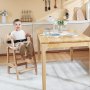 child sitting in VEVOR wooden high chair at a dining table with tableware and flowers in a modern kitchen.