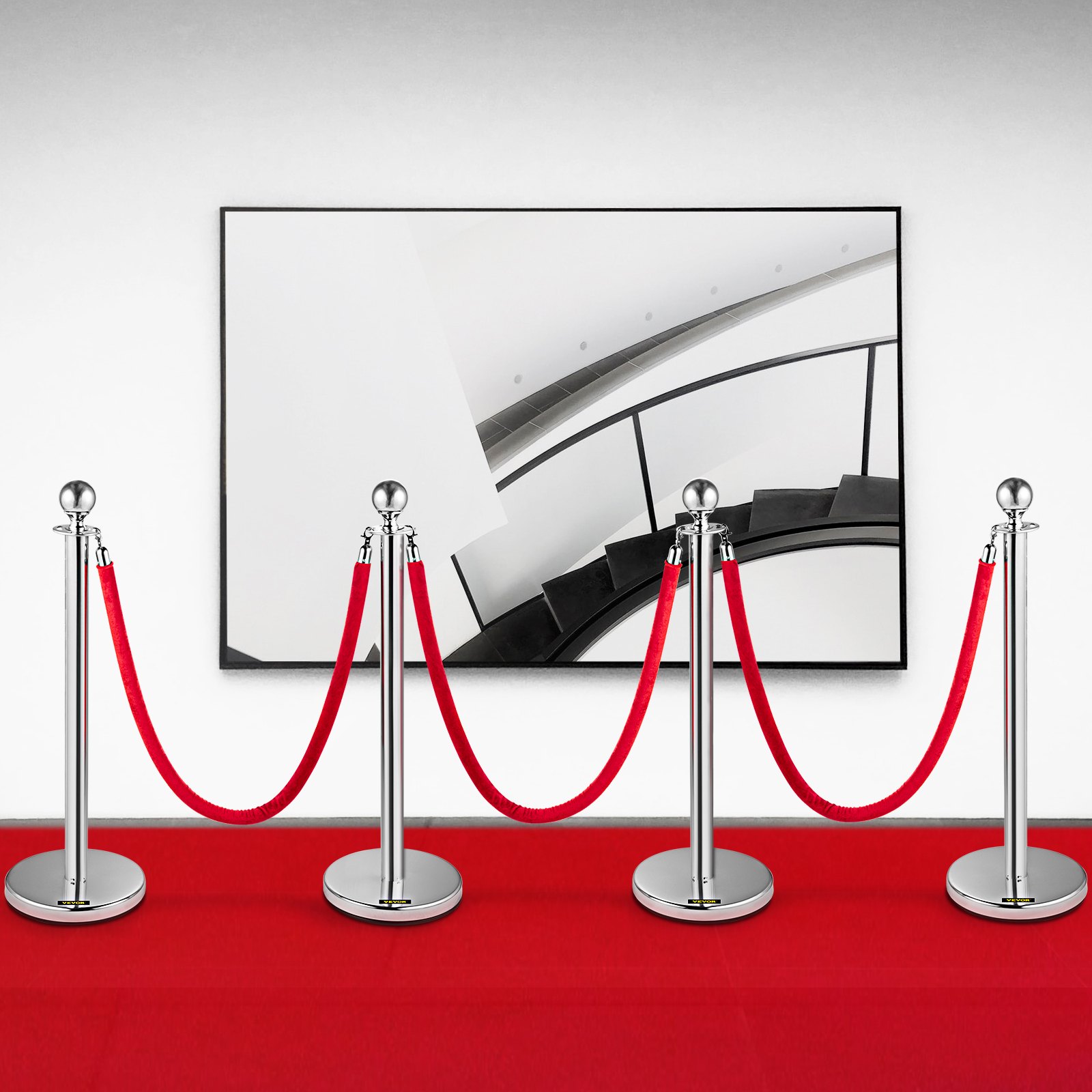 VEVOR stanchion posts with red ropes on a red carpet in front of a framed staircase art.