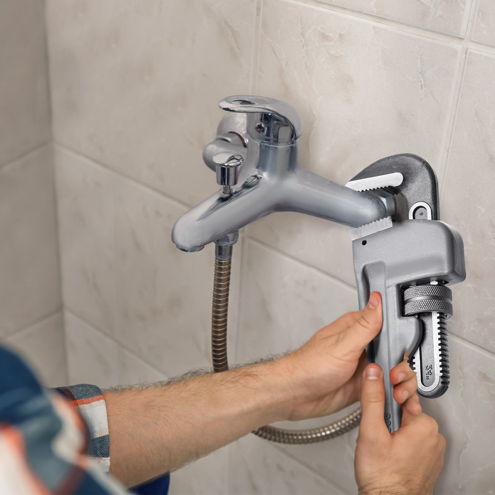 man fixing faucet with a VEVOR pipe wrench against tiled wall.