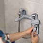 man fixing faucet with a VEVOR pipe wrench against tiled wall.