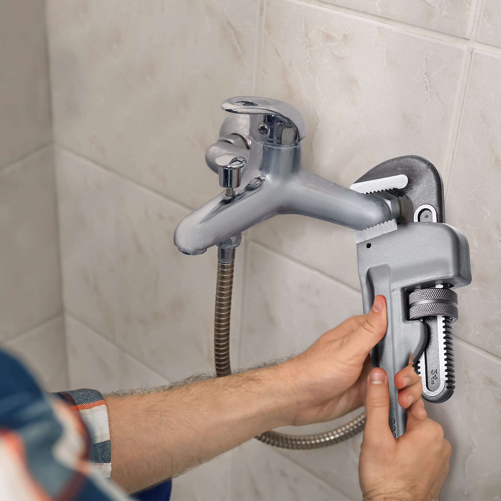 man fixing faucet with a VEVOR pipe wrench against tiled wall.