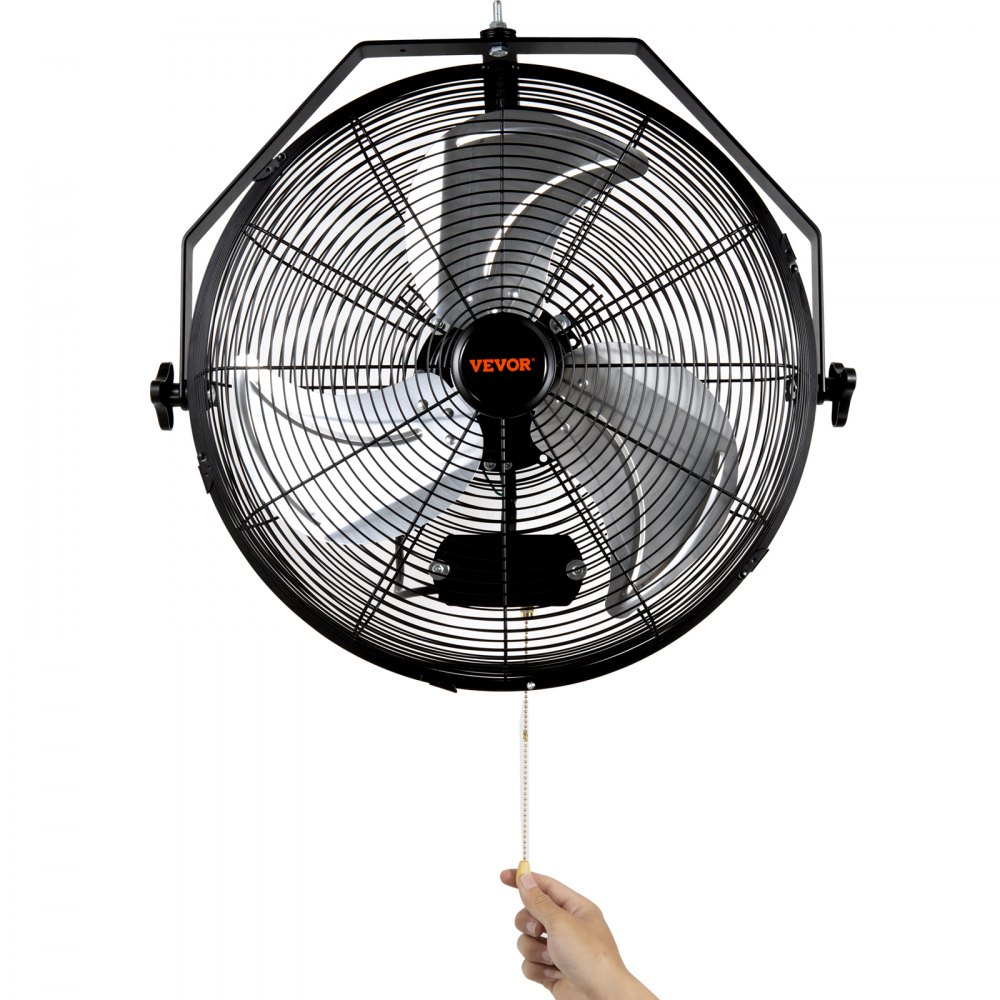 hand pulling a cord to operate a black VEVOR wall mount fan with metal blades and protective grill.