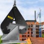 VEVOR beam clamp lifting an i-beam with a construction site backdrop.