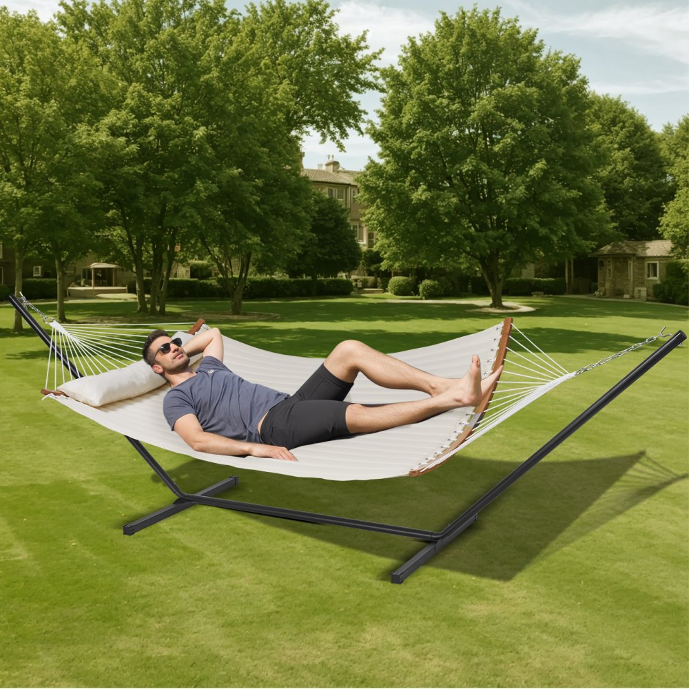 person relaxing on a VEVOR double quilted hammock in a spacious green garden.