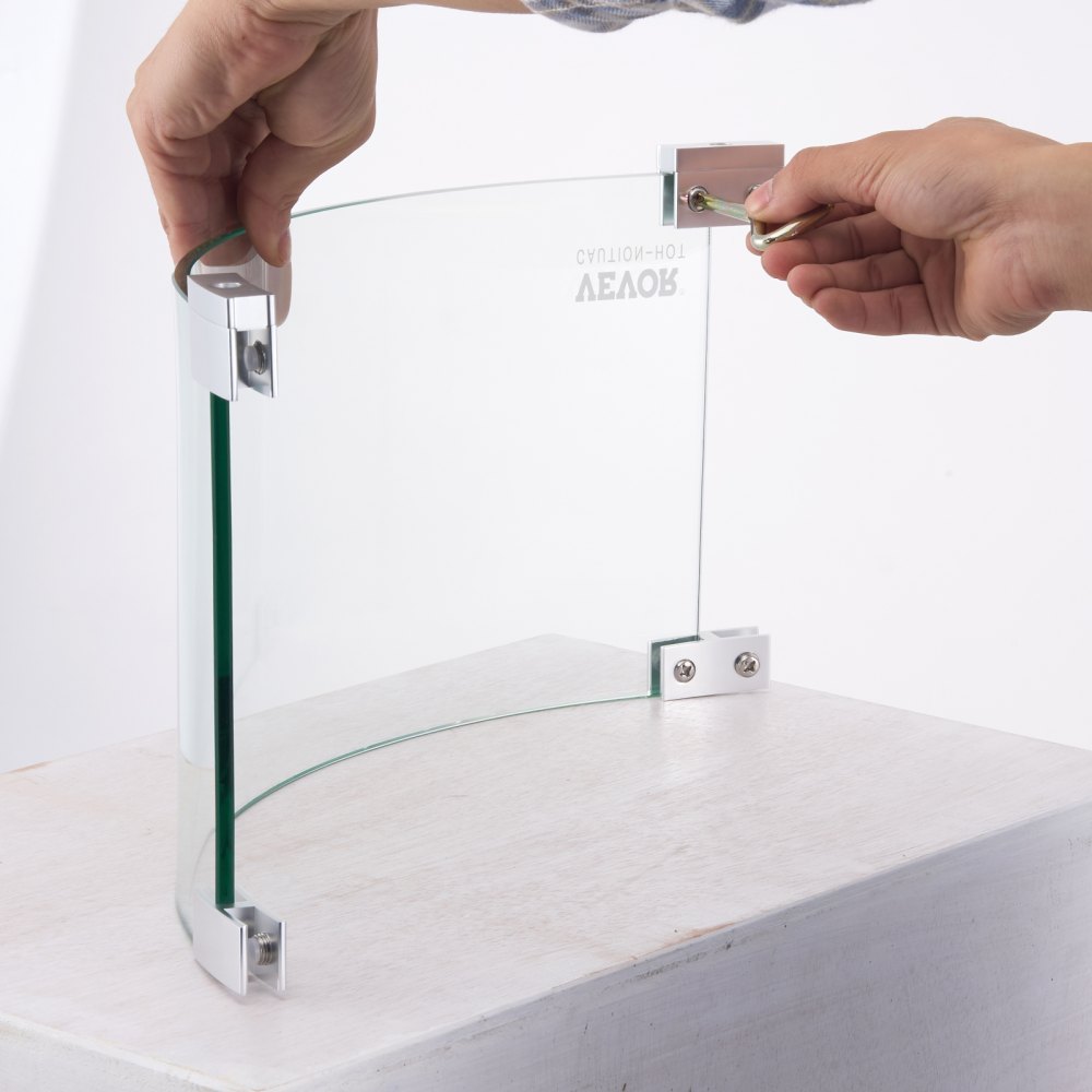 person assembling a VEVOR fire pit wind guard using metal brackets and glass panels.