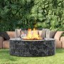 VEVOR fire pit wind guard on a round stone fire pit, with lush green foliage and outdoor seating.