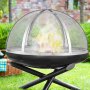 VEVOR firepit spark screen on a black firepit in a garden setting with visible flames and greenery.