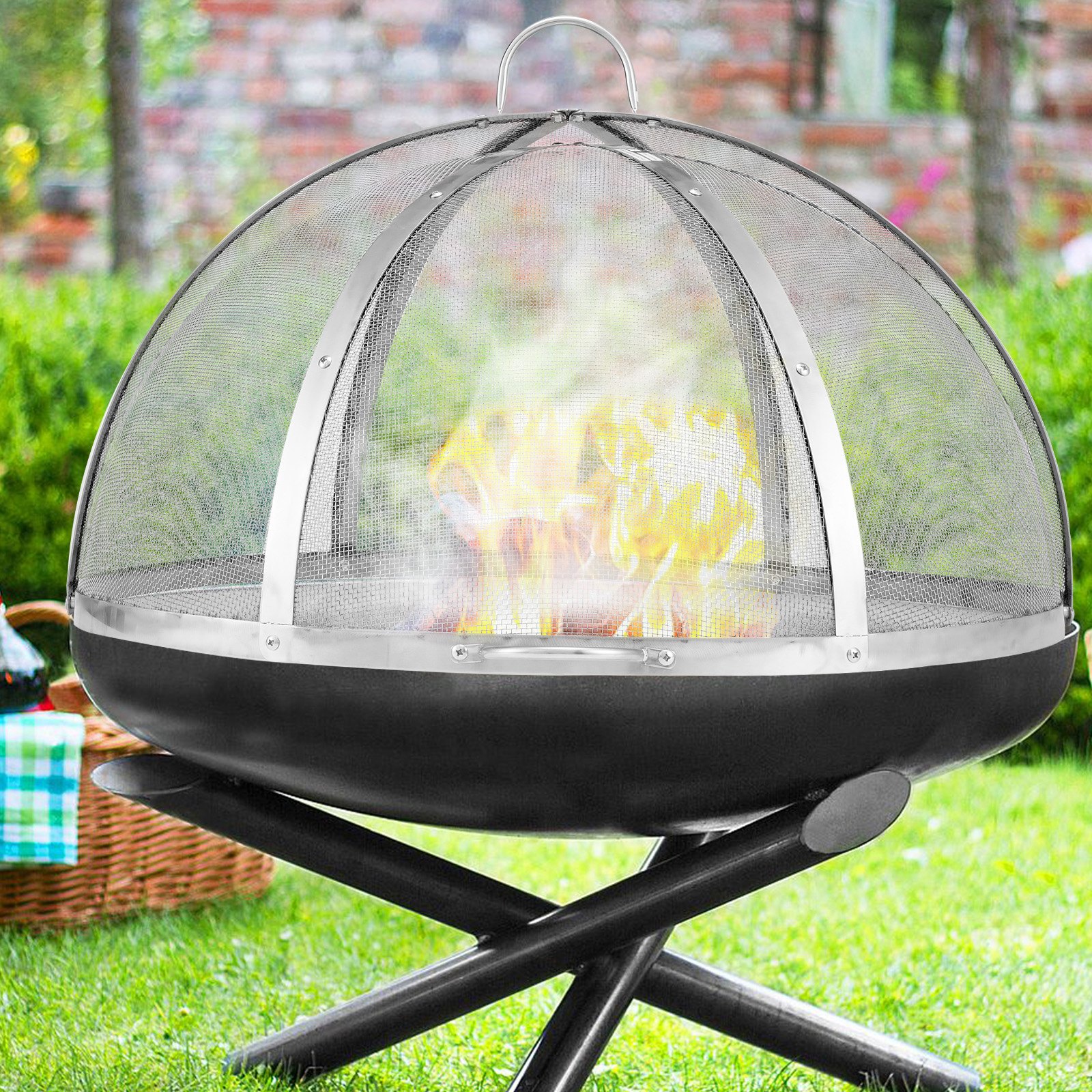 VEVOR firepit spark screen on a black firepit in a garden setting with visible flames and greenery.