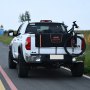 white pickup truck with a VEVOR tailgate pad securing a black bicycle on a rural road.