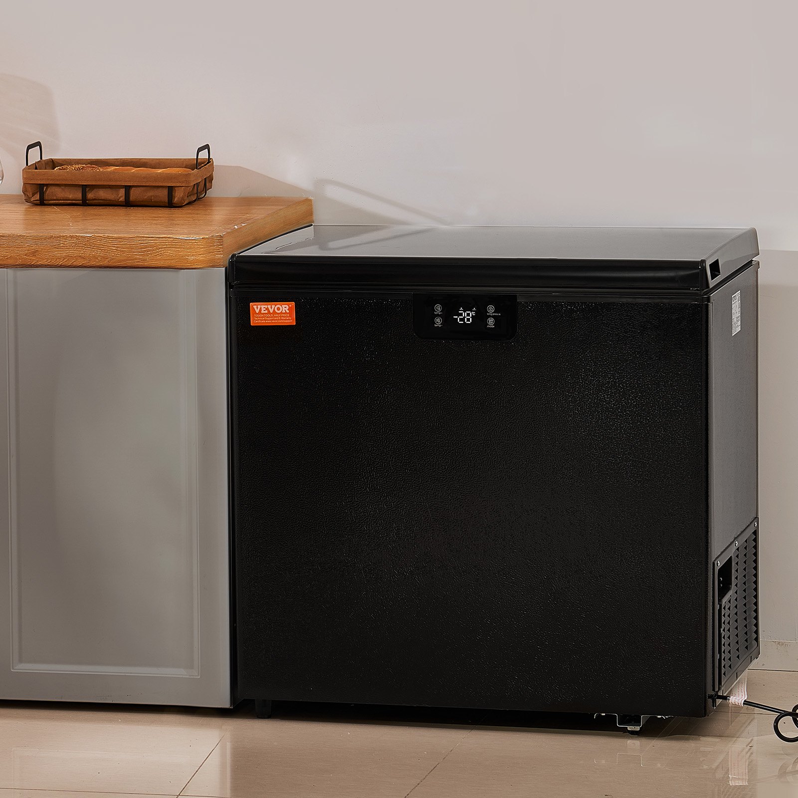 Congelador horizontal VEVOR negro junto a una encimera de madera en un entorno de cocina moderno.