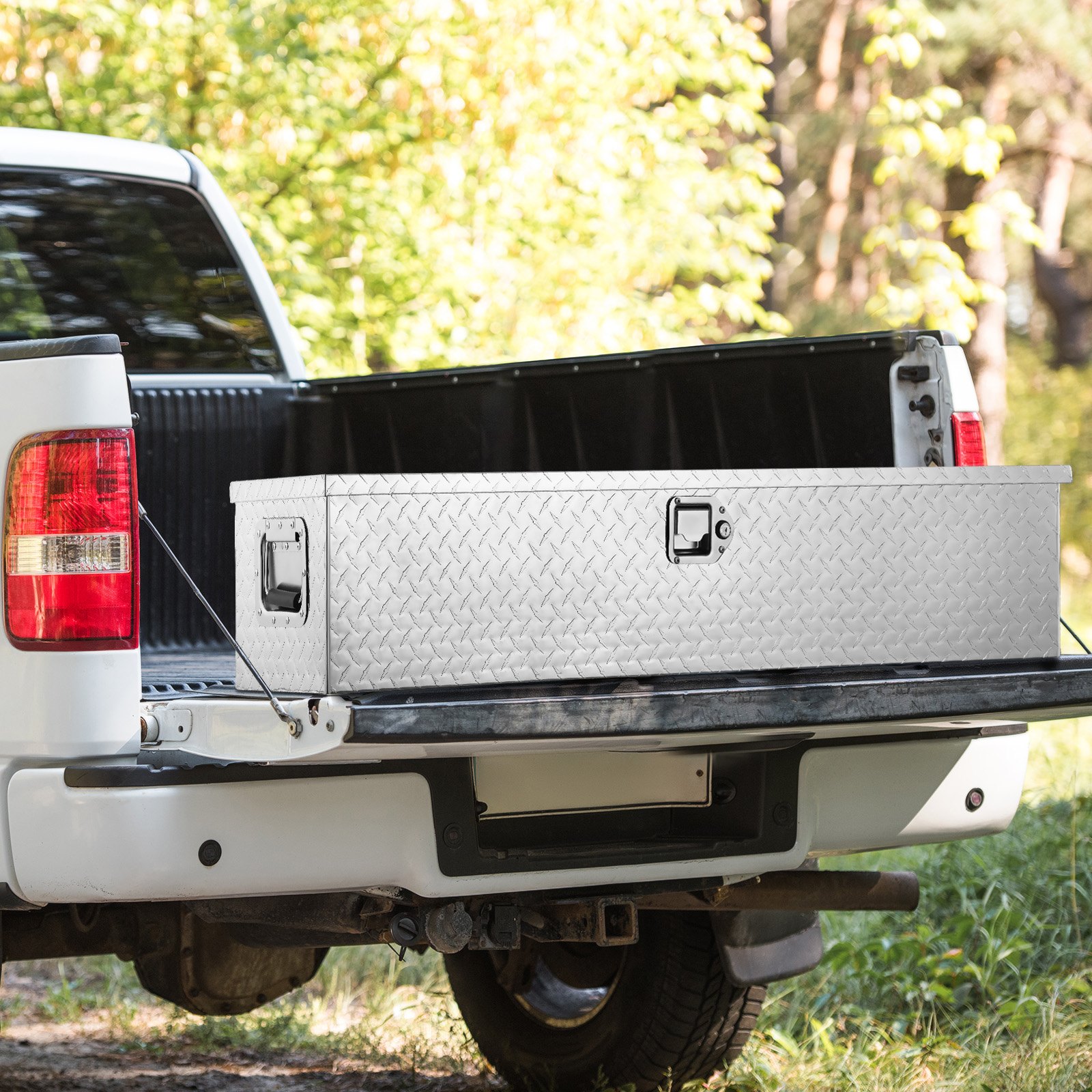 white truck with an open bed featuring a VEVOR truck bed tool box against a forest backdrop.