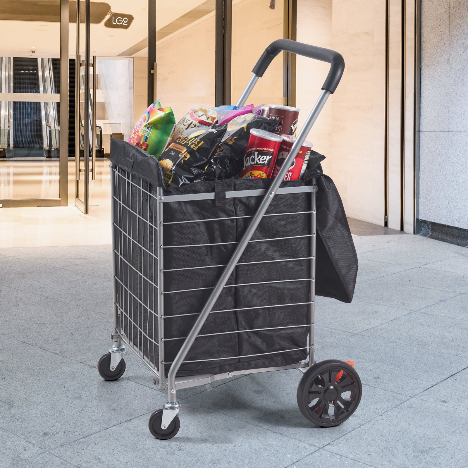 VEVOR folding shopping cart filled with groceries, parked near a modern building entrance.