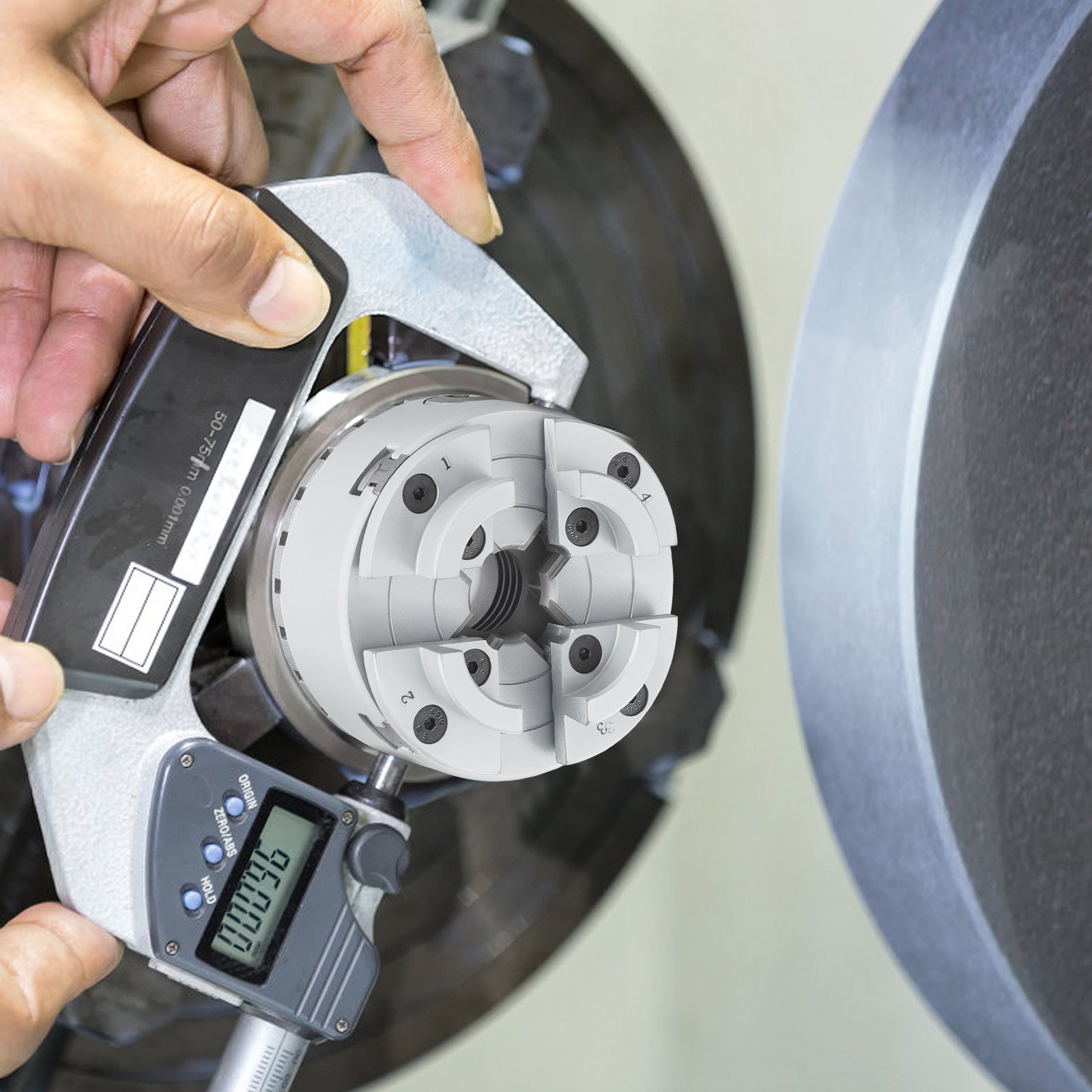 hands measuring a mounted VEVOR lathe chuck with a digital caliper.