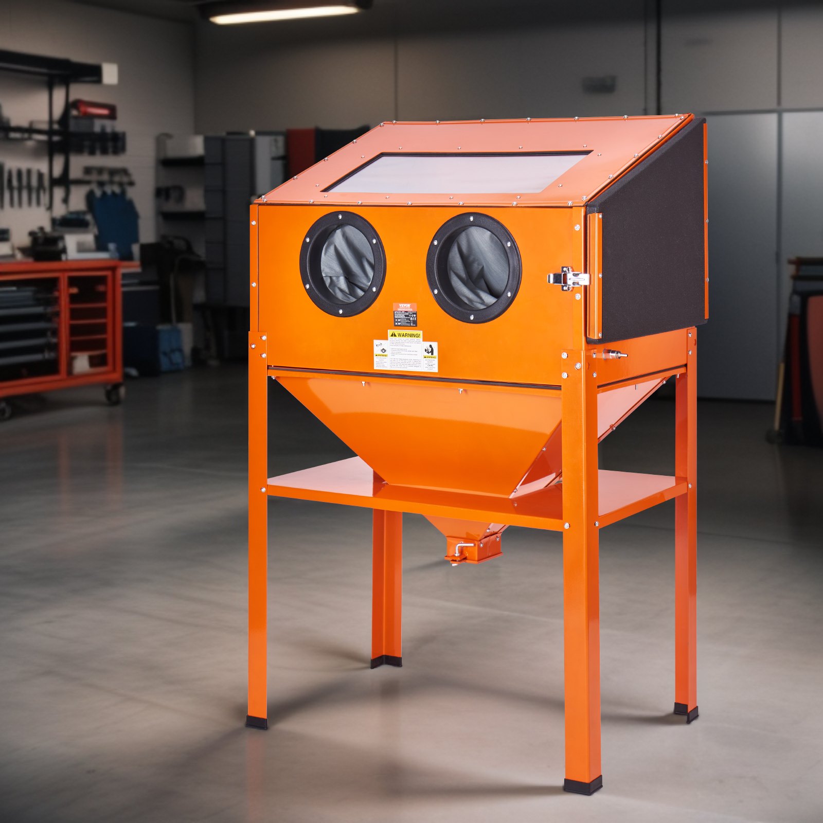 Cabina de chorro de arena VEVOR naranja con guantes y ventana en un entorno de taller.