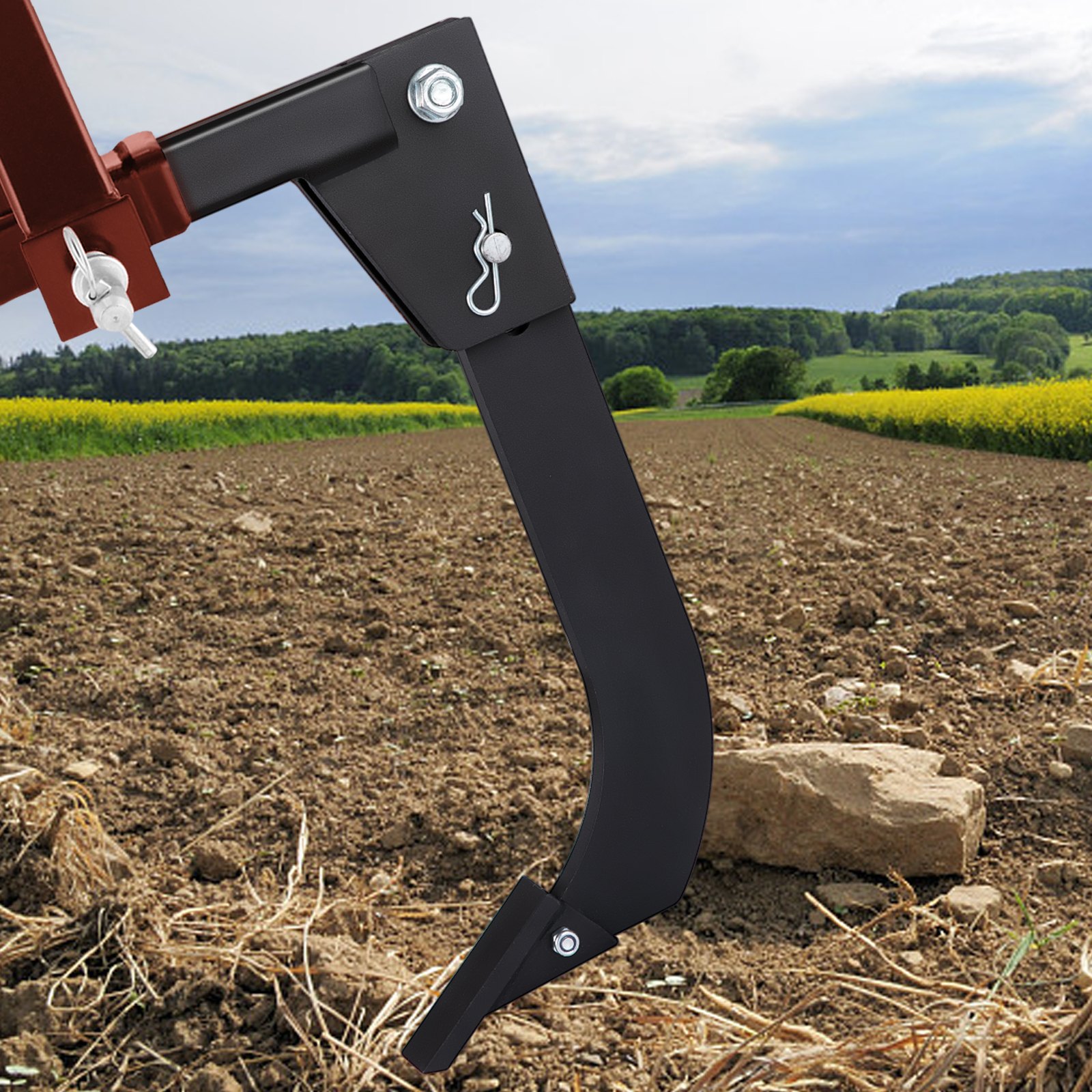 VEVOR hitch mounted ripper working on a plowed field with hills in the background.