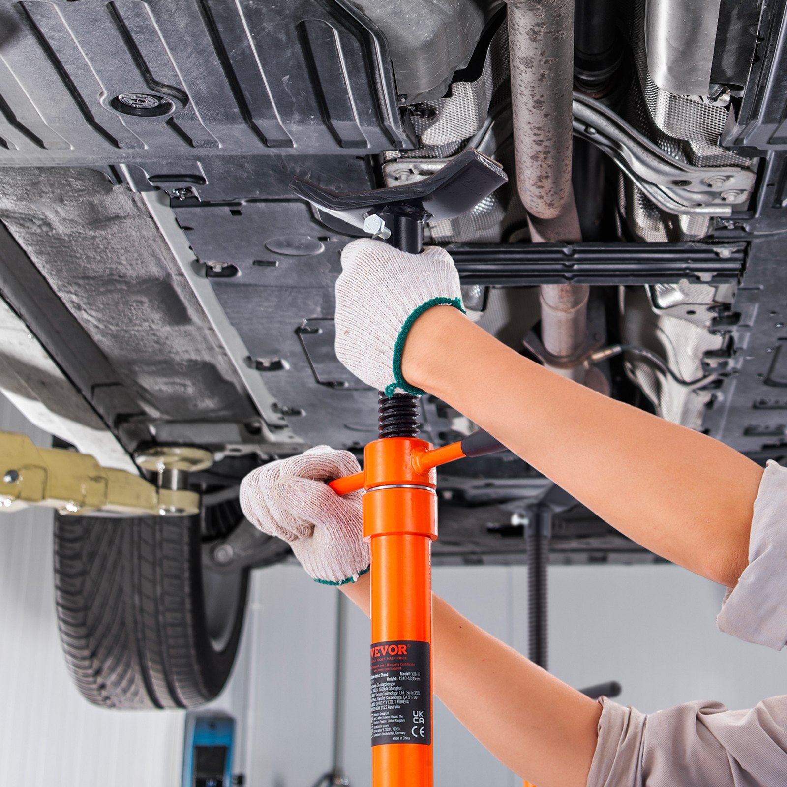 mechanic using VEVOR underhoist support stand to secure vehicle&#039;s undercarriage in a repair shop.