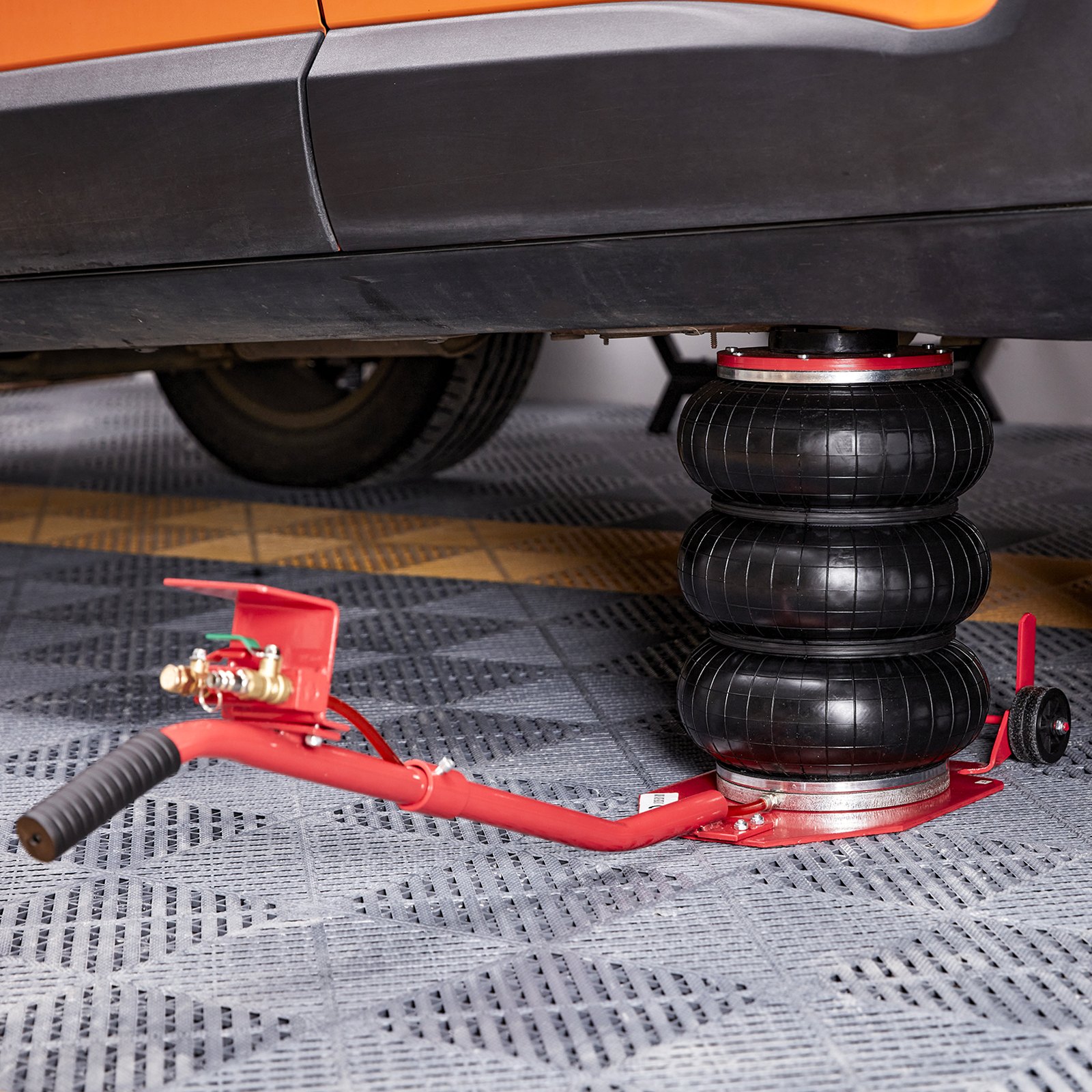 VEVOR air jack lifting an orange car on a patterned floor.