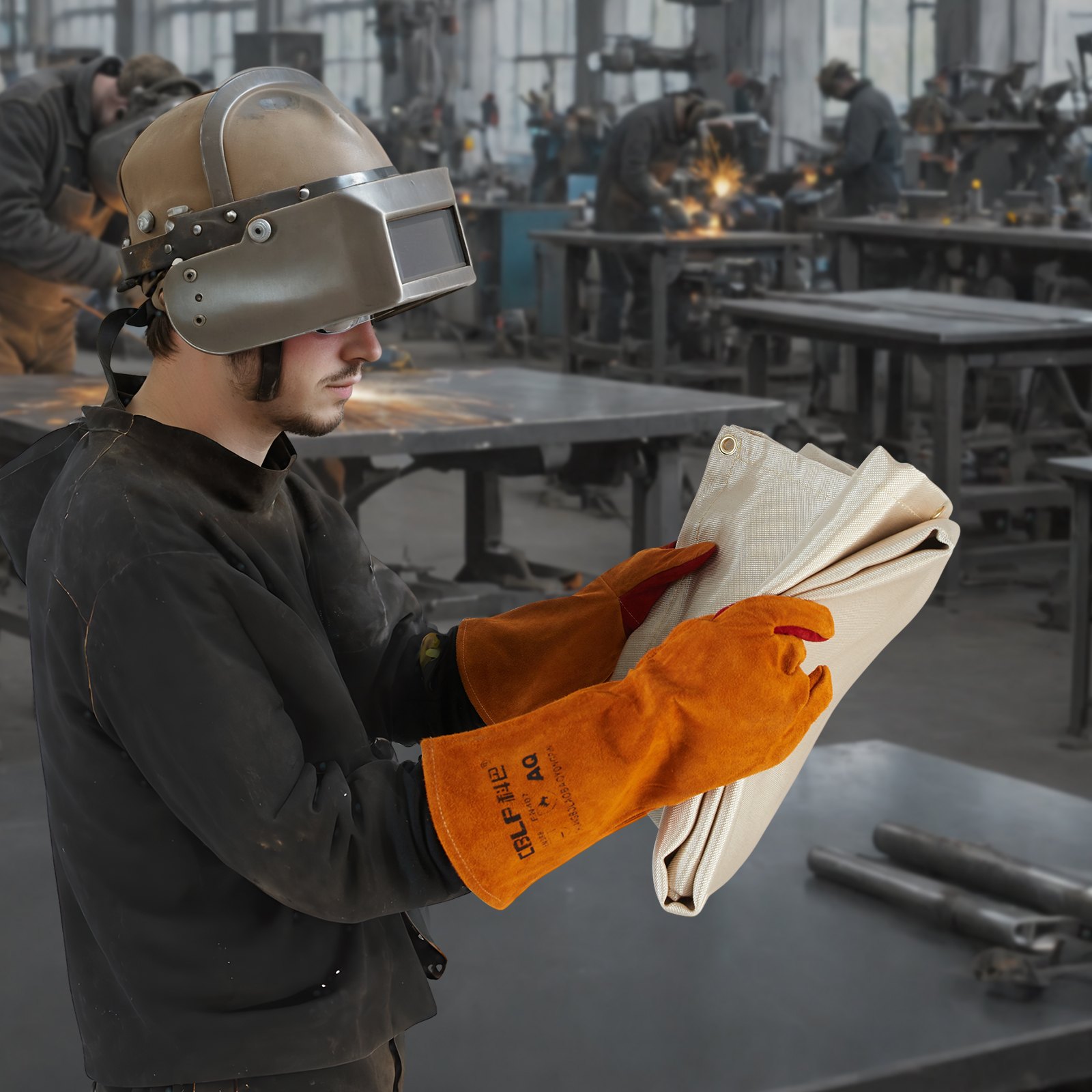 welder holding a VEVOR welding blanket in an industrial workshop setting with colleagues welding in the background.