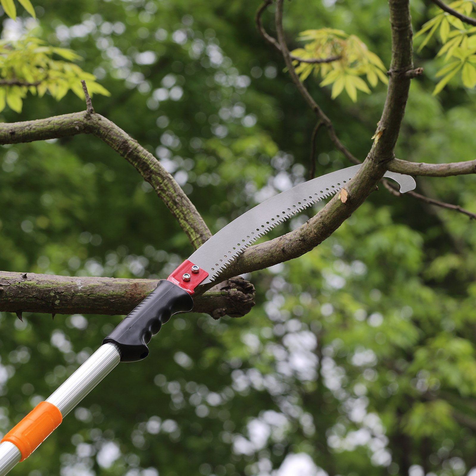 VEVOR manual pole saw cutting a tree branch with green leaves in the background.