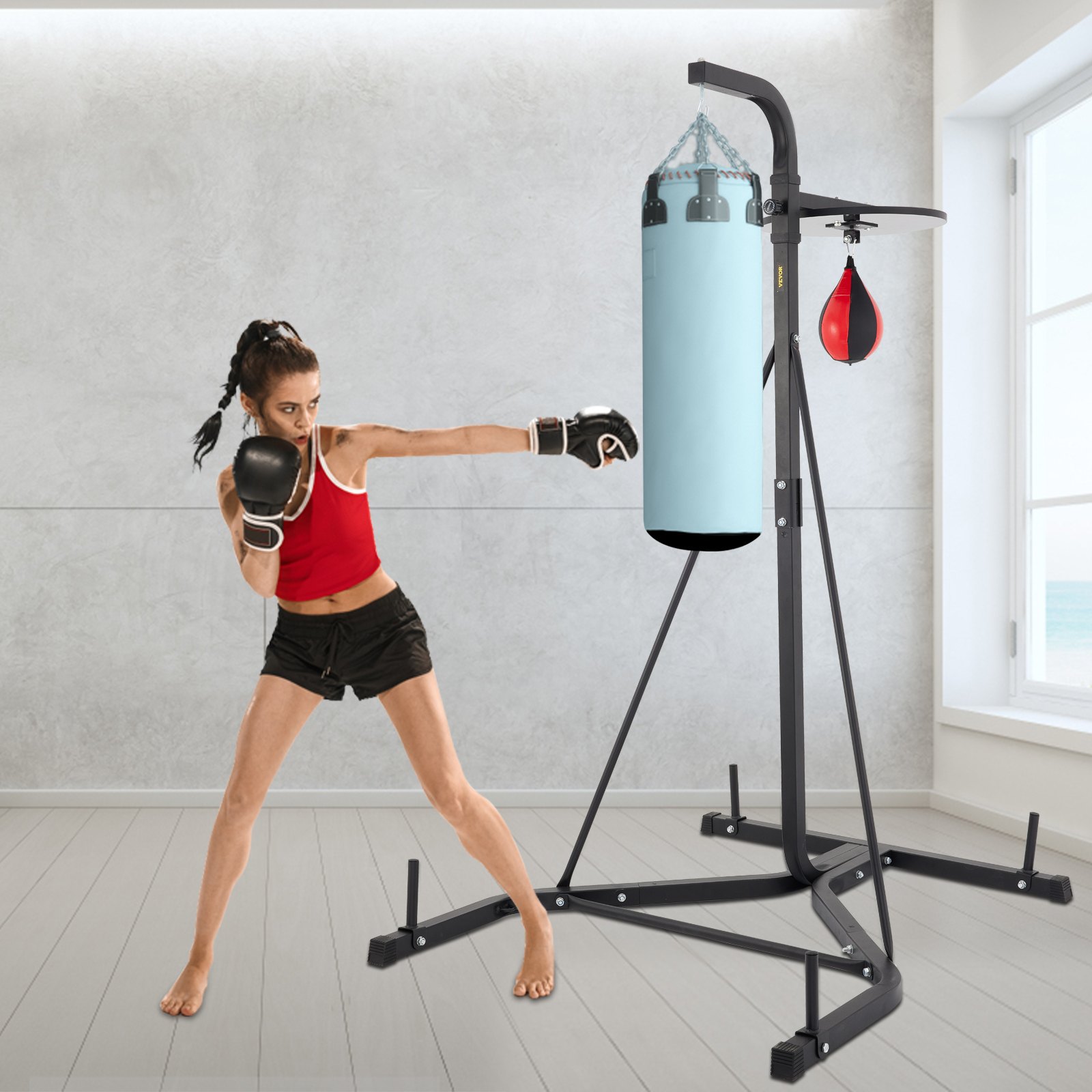 boxer training on VEVOR heavy bag stand in a bright room with ocean view.