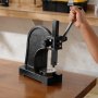 person using VEVOR arbor press on wooden bench in workshop.