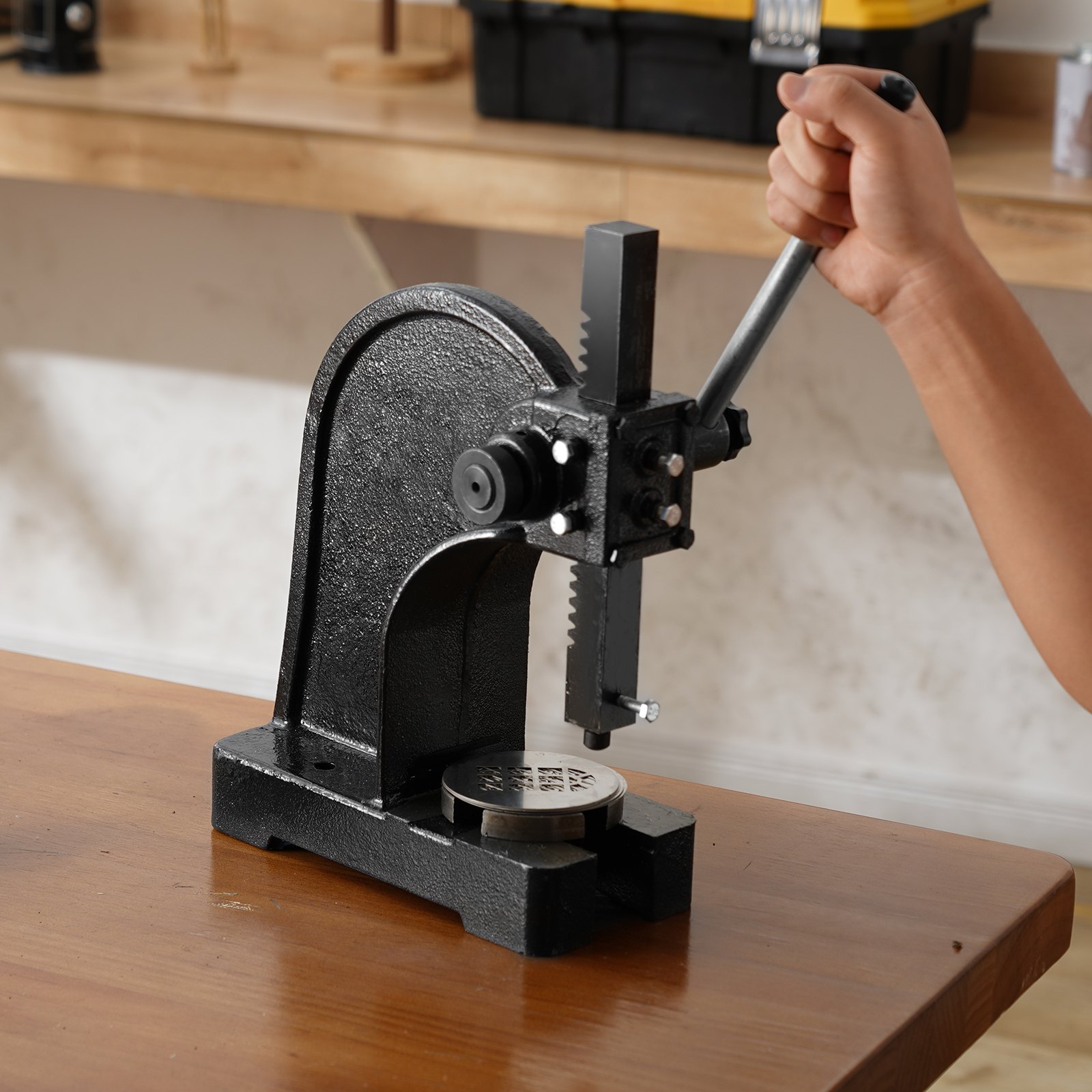 person using VEVOR arbor press on wooden bench in workshop.