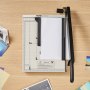 VEVOR paper cutter on a wooden desk with various colorful paper sheets nearby.