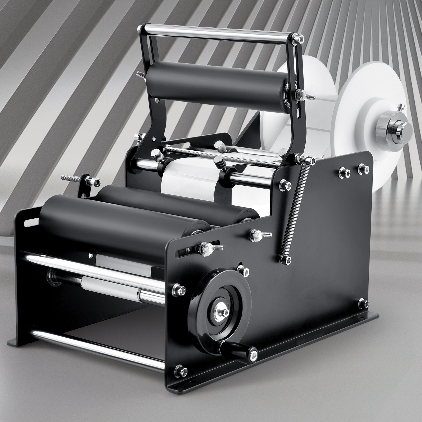 VEVOR manual round labeling machine with rollers and spindle on a striped gray background.