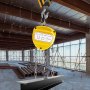 yellow VEVOR chain hoist lifting a steel beam in a construction site.
