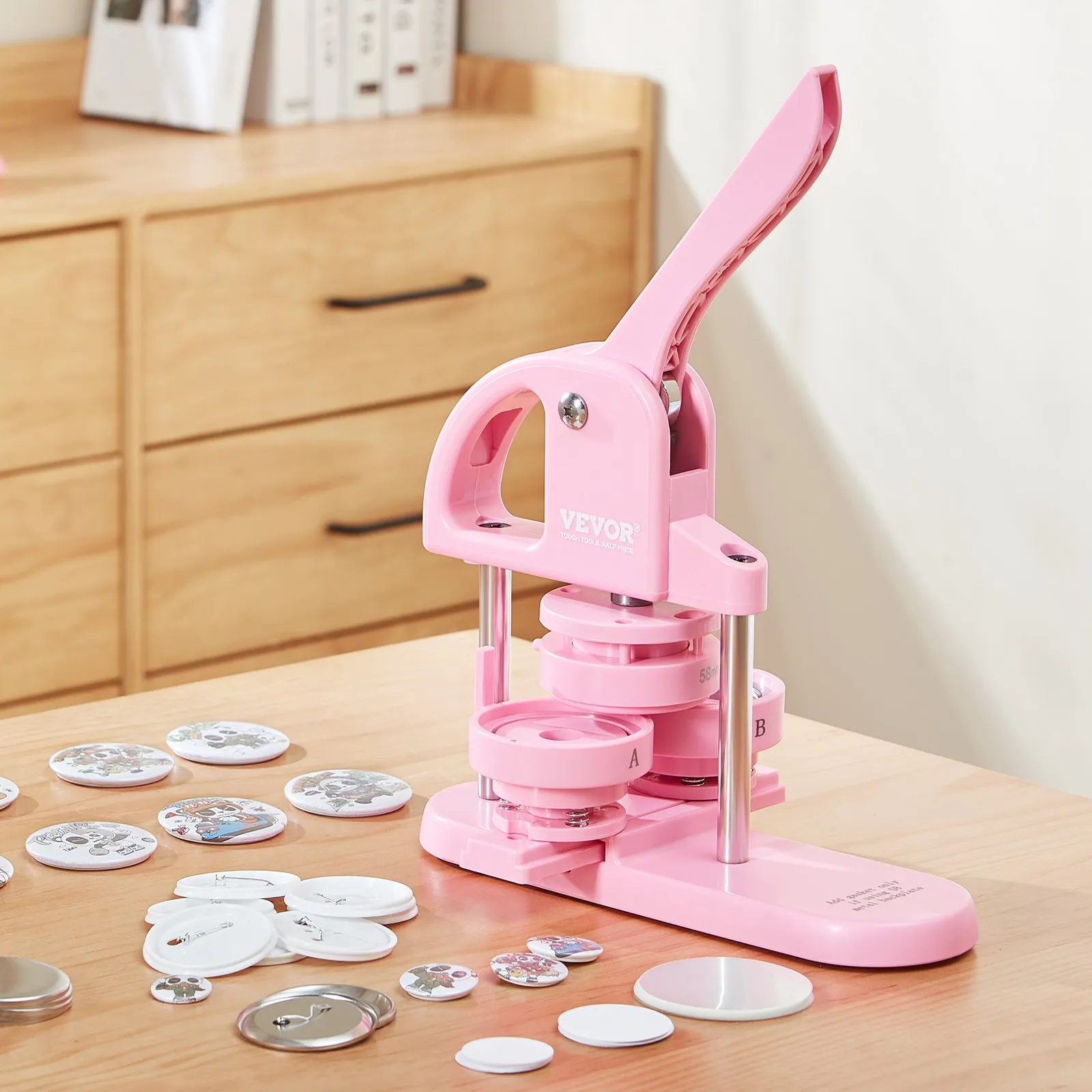pink VEVOR button maker on a wooden table with various button parts scattered around.