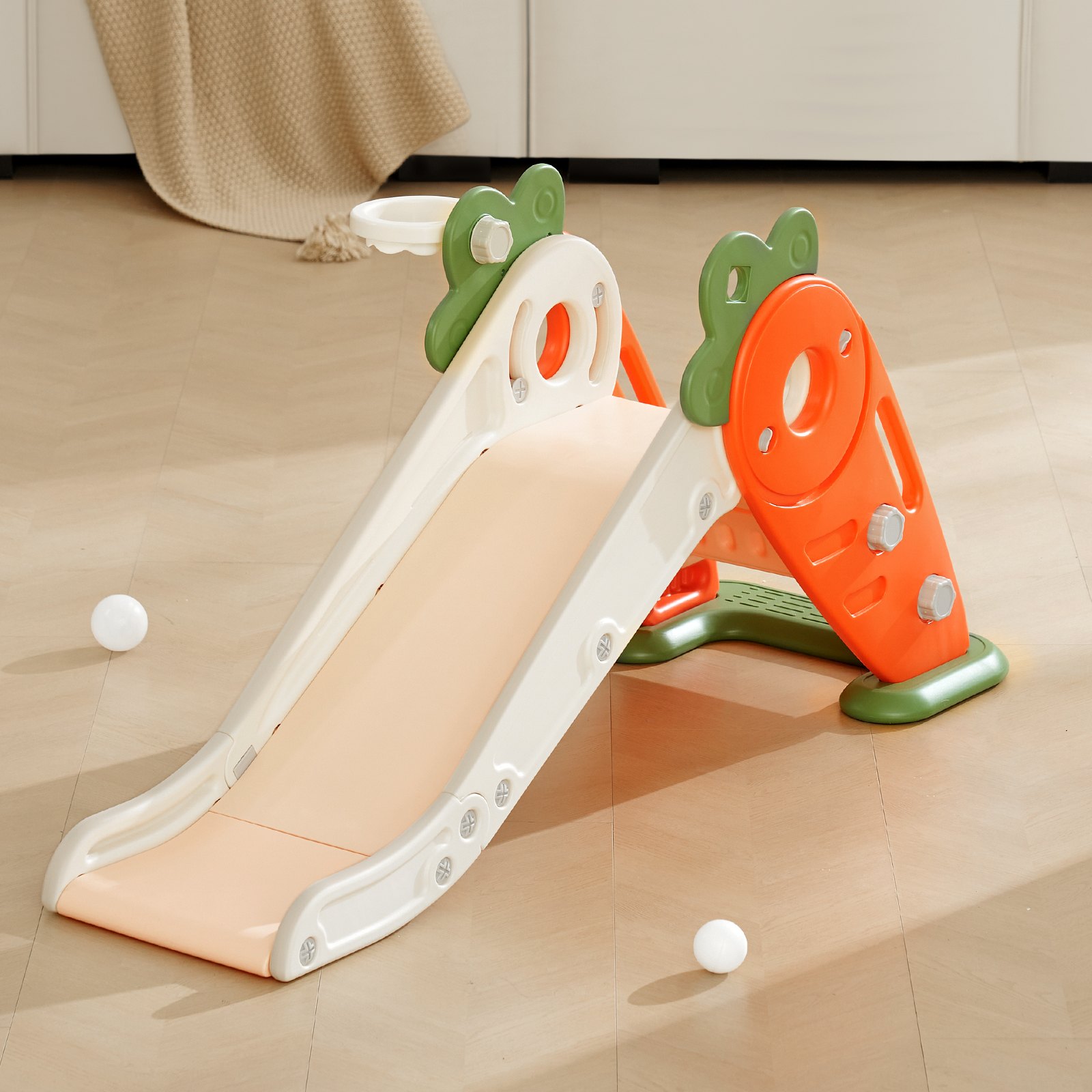 VEVOR toddler slide in white, green, and orange, with a small basketball hoop, set on a wooden floor.