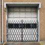 VEVOR folding security gate in front of a closed industrial garage door.