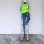 worker in safety gear climbs a VEVOR telescoping ladder against a white brick wall.